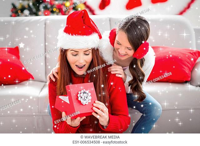 Composite image of festive mother and daughter with a christmas gift