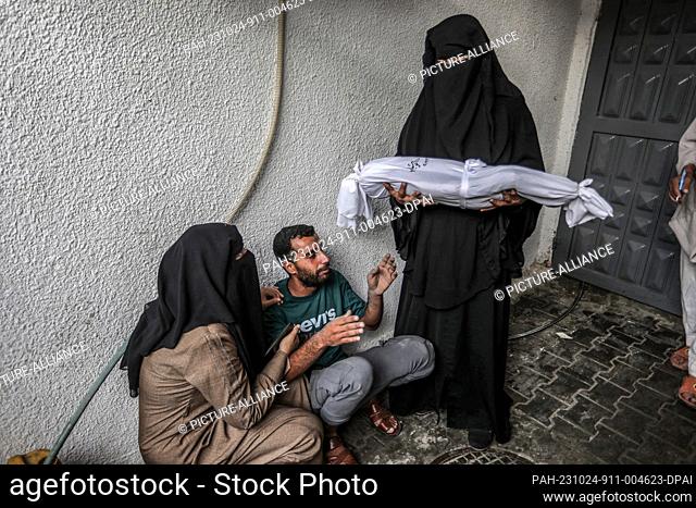24 October 2023, Palestinian Territories, Rafah: A woman cries hands the body of a dead child, who was killed in an Israeli strike on their home