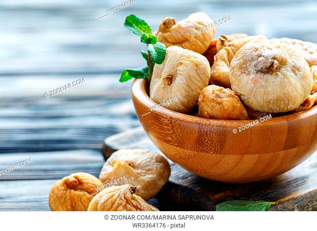 Sweet dried figs in a bowl on wooden table, selective focus