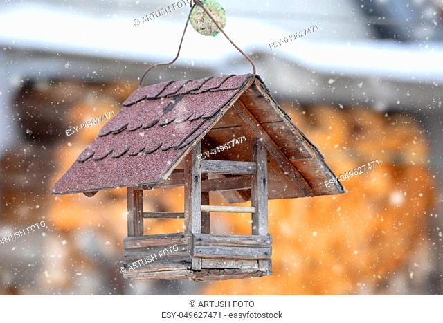 hanged wooden Bird Feeder, tree house for the feeding garden birds with snow in cold day