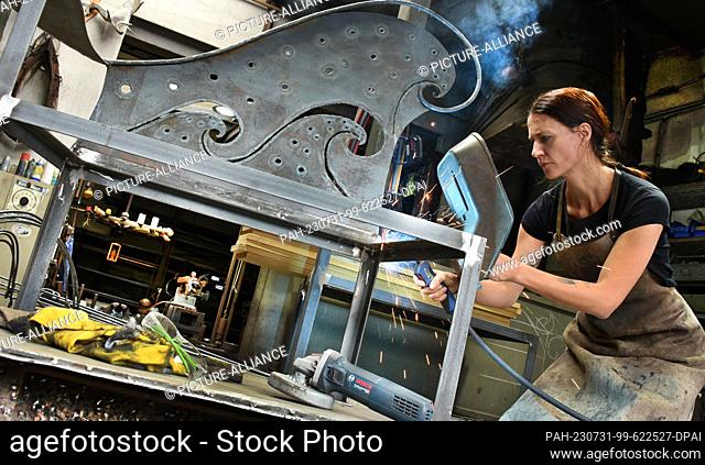 27 July 2023, Saxony, Hohenprießnitz: Blacksmith and metal designer Marika Widdermann works on a two-seater bench in her father Roger Widdermann's forge