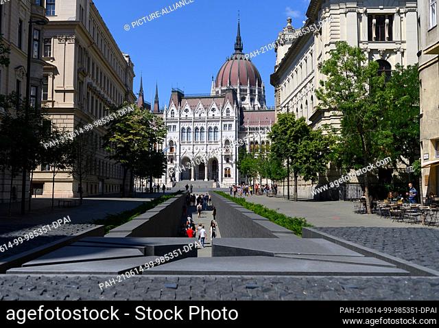 14 June 2021, Hungary, Budapest: Tourists walk out of the National Unity Monument, the Trianon Monument, on Lajos Kossuth Square in front of the Parliament