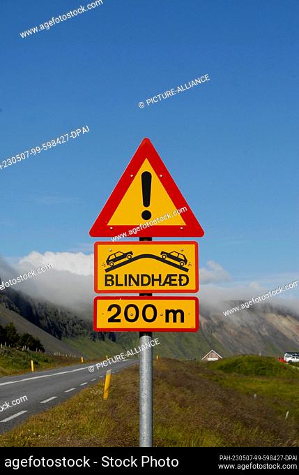 23 July 2022, Iceland, Snaefellsnes: A warning sign uses symbols and the Icelandic word ""BLINDHÆD"" to indicate a ""blind hilltop"" (oncoming traffic not...