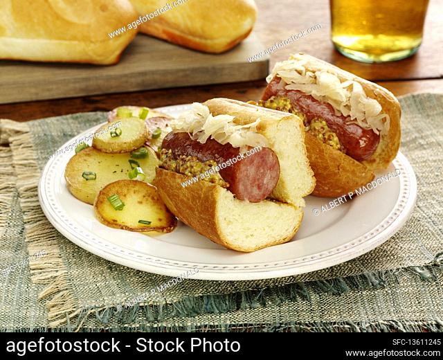 A polish sausage, sauerkraut and whole grain mustard sandwich with sauteed potatoes