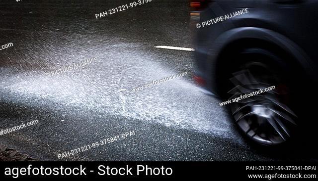 21 December 2023, Lower Saxony, Osnabrück: Water on a road splashes up behind a vehicle. The German Weather Service is expecting storms