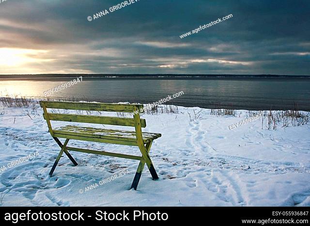 Empty bench at seaside in late winter evening