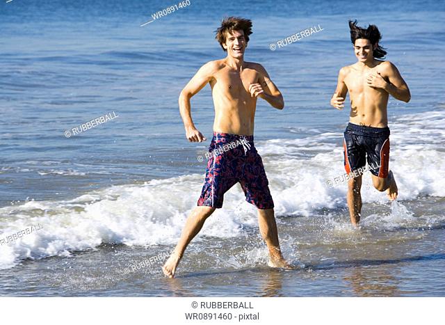 Two young men running on the beach
