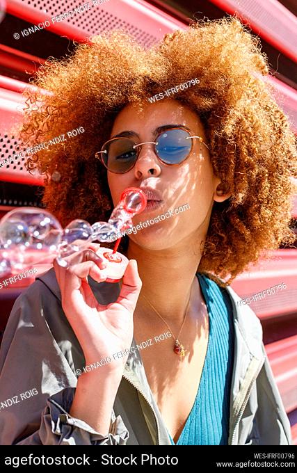 Afro young woman blowing bubbles on sunny day