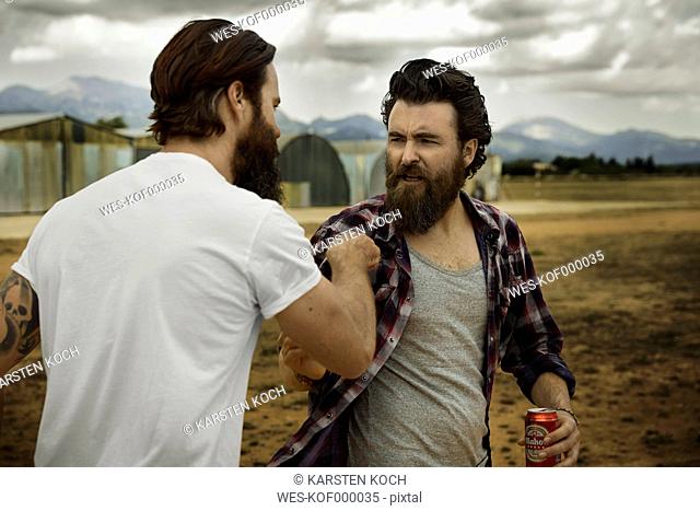 wo men with full beards fighting in abandoned landscape