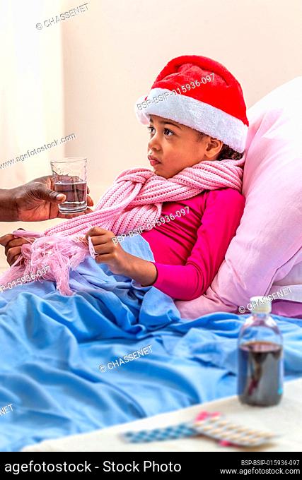 Little girl wearing Santa hat receiving her medicine while she is in hospital