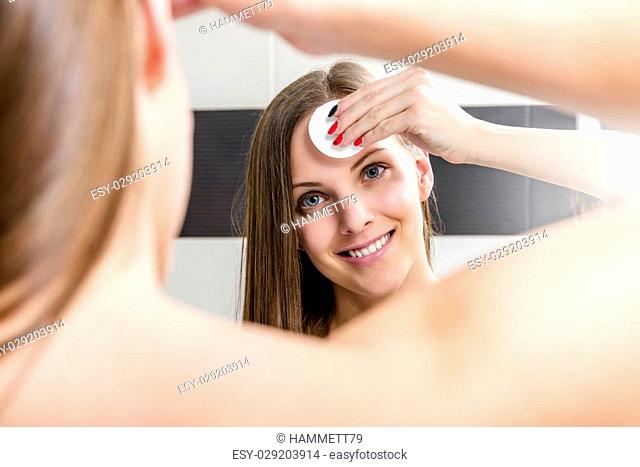 Beautiful brunette woman removing makeup from her face