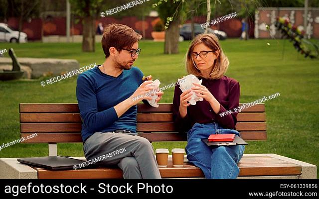 Hungry young business man enjoy a snack. Eat outdoors. Friends having a packed snack in a park. Friends eats with gusto