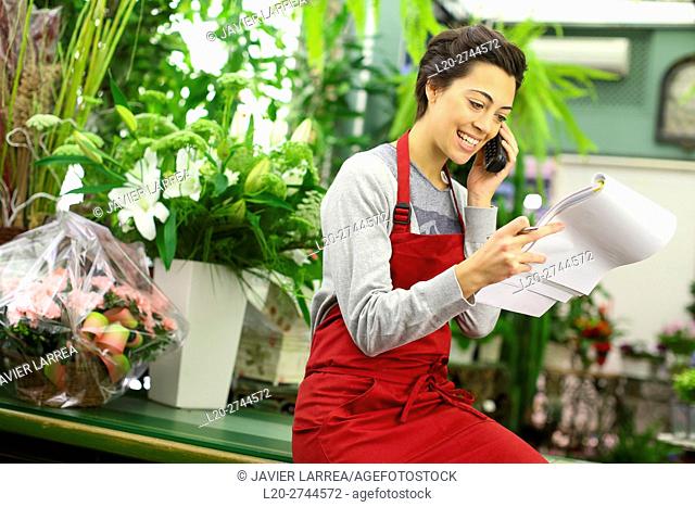 Florist in flower shop taking an order from a customer on the phone