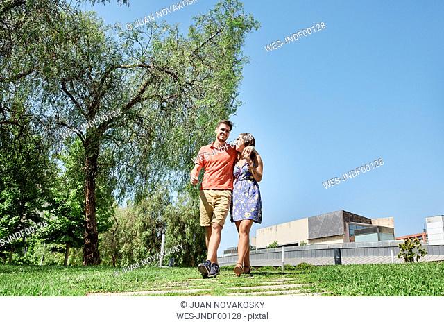 Happy young couple walking trough a park