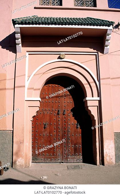 Street. House door. Archway. Red painted wood. Stud decoration. Medina