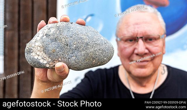 27 September 2023, Schleswig-Holstein, Kiel: Hobby researcher Thomas Freiberg shows the stone in which the fossilization of a starfish can be seen on the left