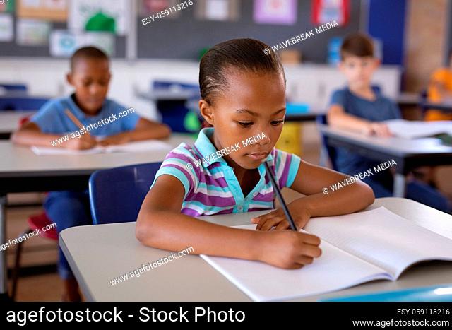African american girl studying while sitting on her desk in the class at school
