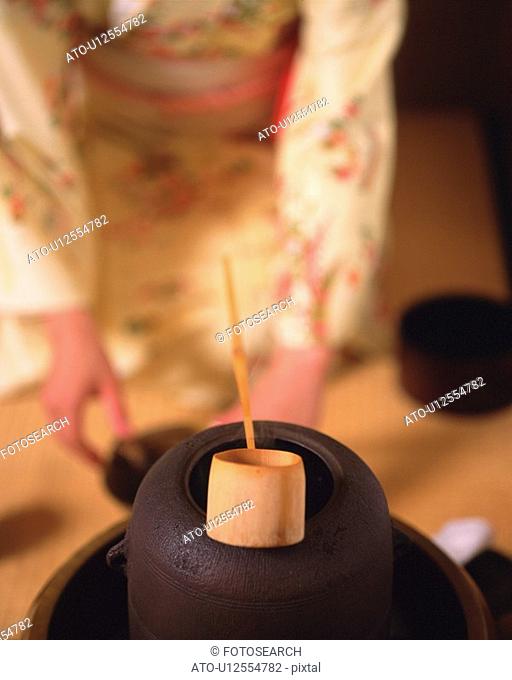 Woman in kimono setting up for tea ceremony, front view, Japan, differential focus