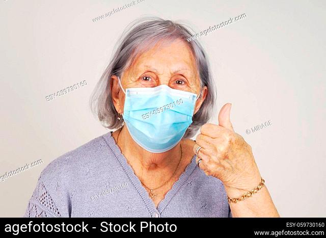 Happy masked senior woman with thumb up after receiving COVID vaccine
