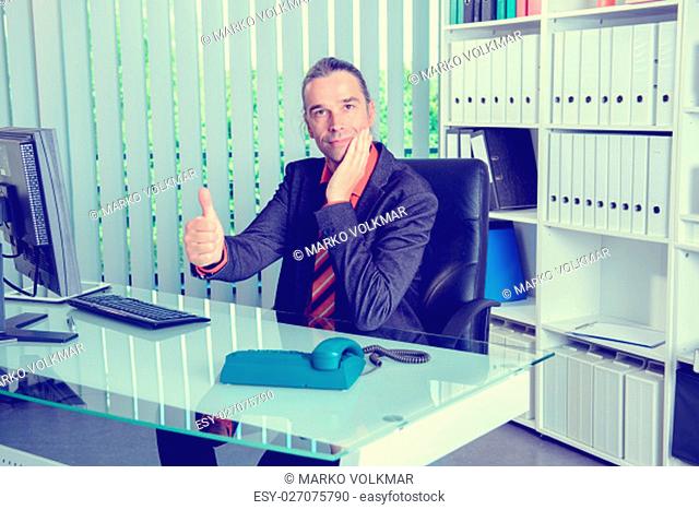 young business man at his desk with thumb up