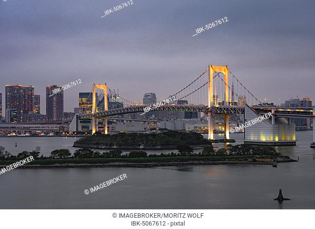 View of skyline with skyscrapers and illuminated Rainbow Bridge in the evening, Odaiba, Tokyo, Japan, Asia