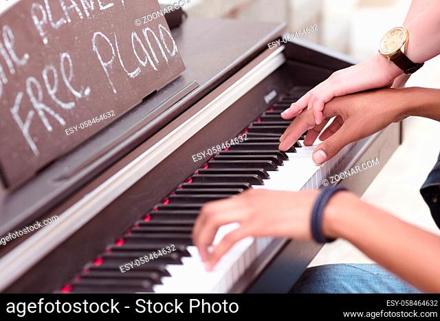 Closeup of keyboard of piano. Man playing piano while lady explaining him something. Professional musician playing outdoors