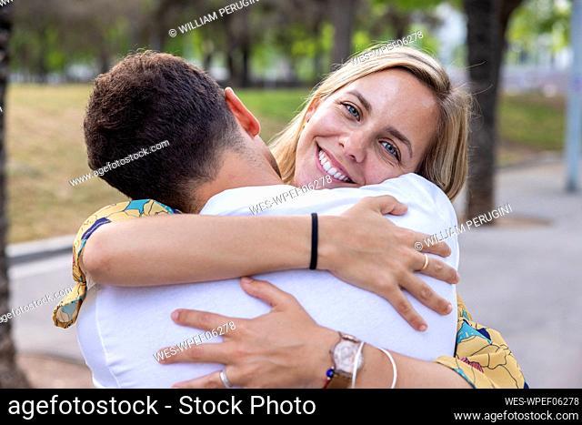 Smiling woman hugging boyfriend at park