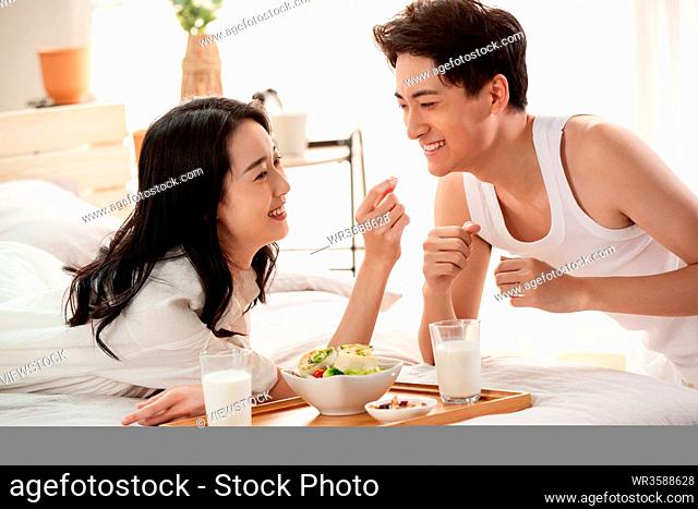 Happy young couple to have breakfast in bed