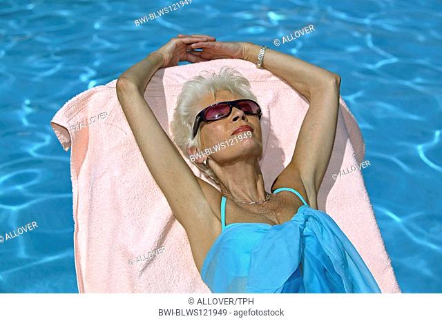 whitehaired woman sunbathing at the pool