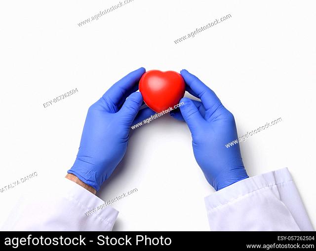 two hands in blue latex gloves holding a red heart, donation concept, close up