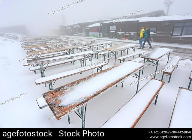 20 April 2023, Saxony-Anhalt, Schierke: The tables and benches of an outdoor restaurant on the Brocken are covered in snow