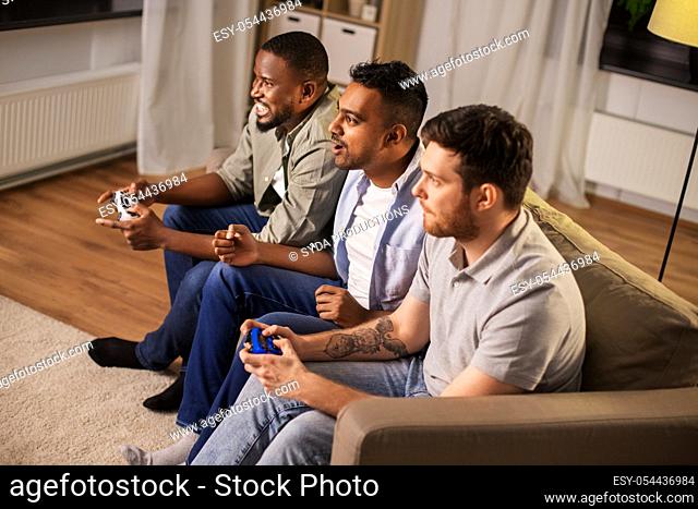 happy friends playing video games at home at night