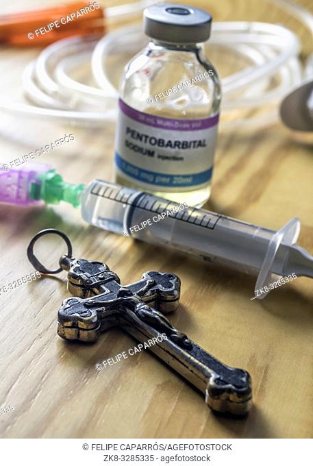 Vial with doses of pentobarbital next to a crucifix, Debate between life and death, religious belief in the face of euthanasia, conceptual image
