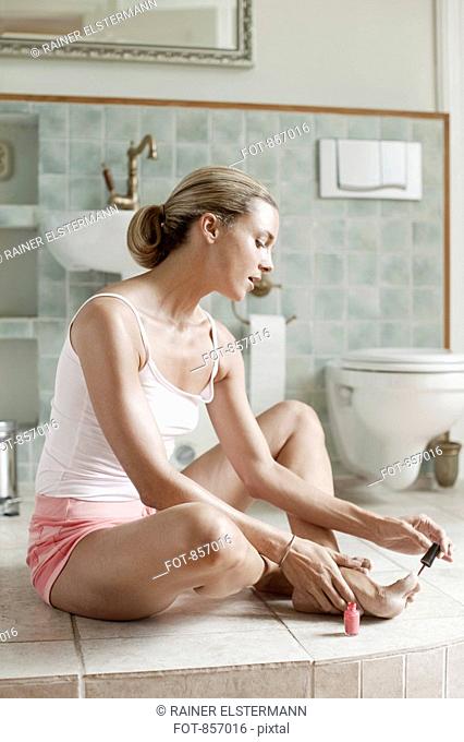 A woman painting her toenails in a health spa bathroom