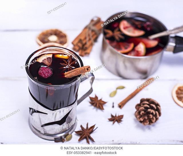 mulled wine in a glass with an iron cup holder on a white wooden background, top view