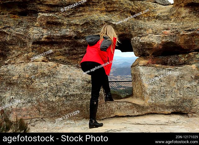 A woman looking through the cave opening with views out over the valley