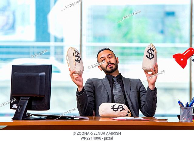Happy businessman with money sacks in the office