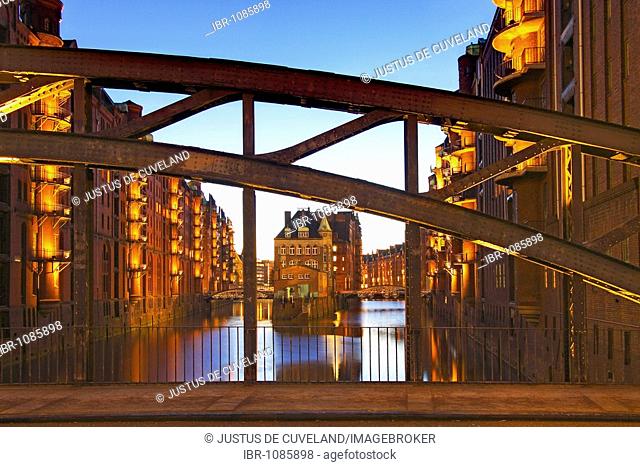 View through Poggenmuehlenbruecke bridge towards Wasserschloesschen, water castle, in Speicherstadt, old warehouse district, in evening light, port of Hamburg