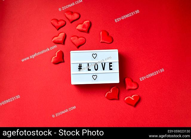 Love lightbox message with red hearts on red background. Top view flatlay