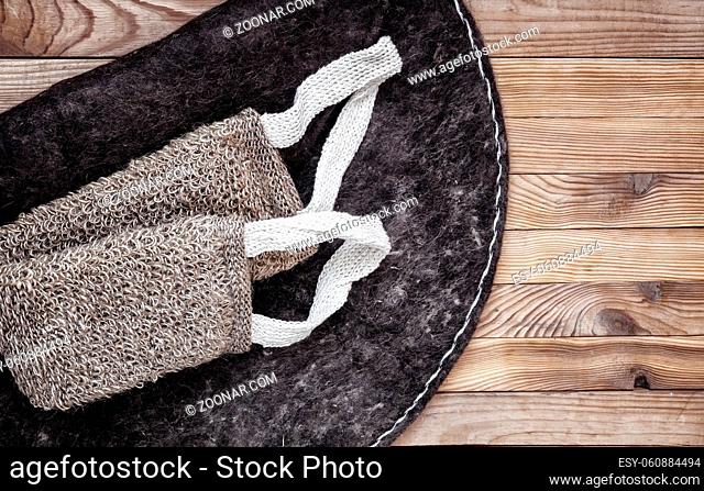 Accessories for visiting a bath or sauna on a wooden background: a washcloth and a bath mat. Top view with copy space. Flat lay
