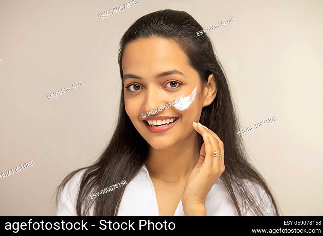 beautiful woman applying cream on her face