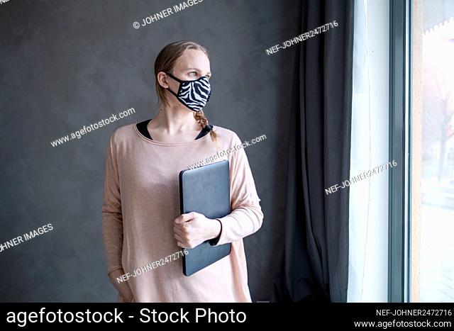 Woman with face mask holding laptop