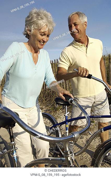 Close-up of a senior couple holding bicycles and walking