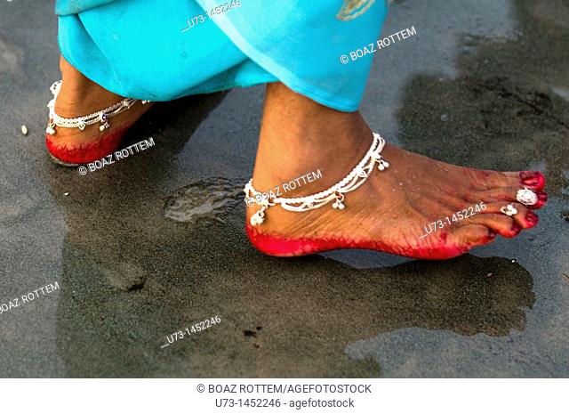 Indian woman's feet decorated with anklet and red color