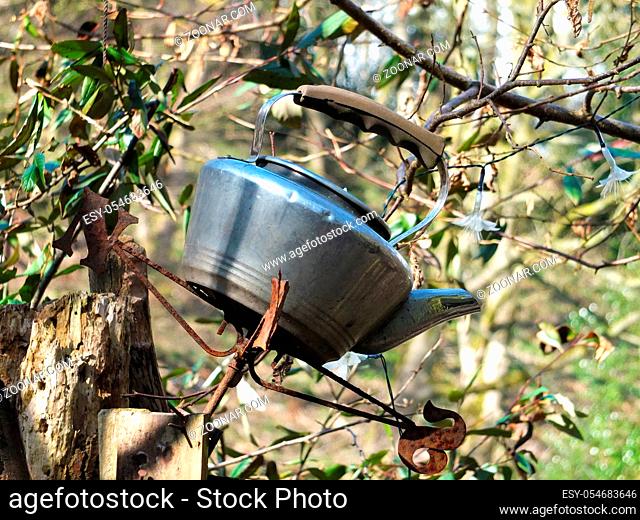 old discarded kettle on top of a gate post in a rural setting surrounded by trees