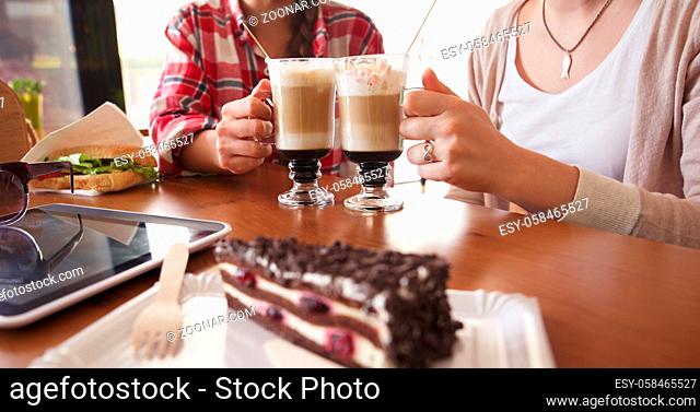 Toned image of best friends meetig or date in cafe or restaurant. Ladies having round or cheers with cups of latte