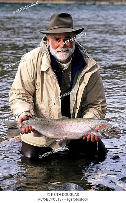 Flyfisherman holding Bulkley river steelhead prior to release, Smithers, British Columbia, Canada