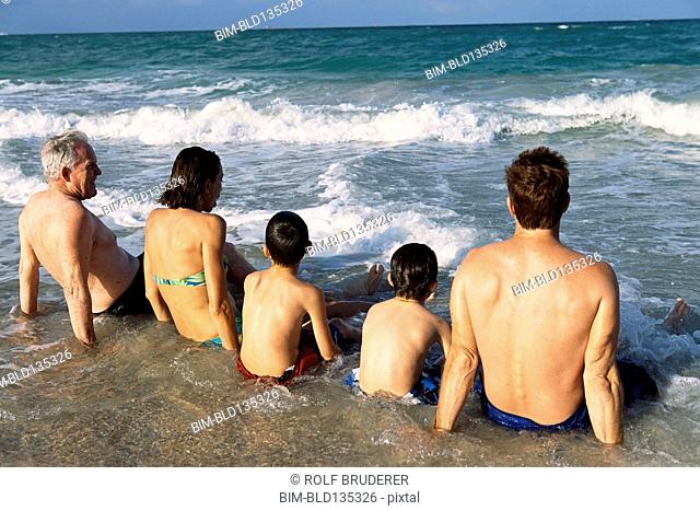 Family sitting in waves on beach