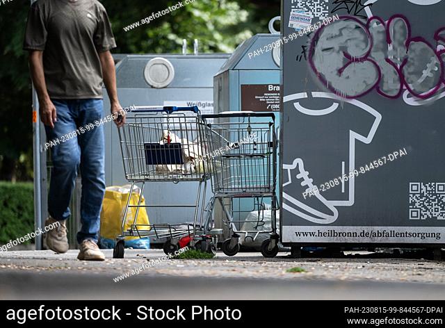 15 August 2023, Baden-Württemberg, Heilbronn: Garbage and shopping carts are in front of a used clothing container and glass containers