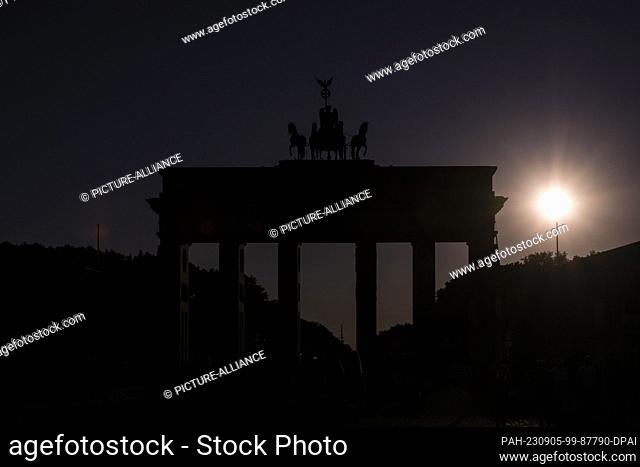05 September 2023, Berlin: In the light of the setting sun, the Quadriga on the Brandenburg Gate can only be seen as a silhouette